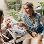 Woman talking to another woman with baby in the background