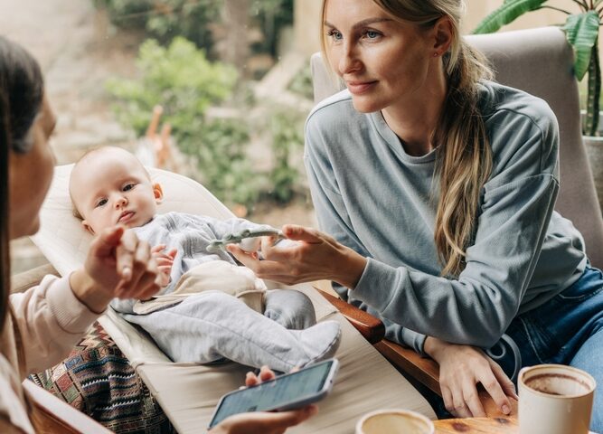 Woman talking to another woman with baby in the background